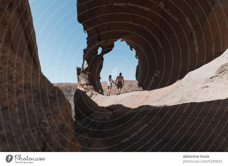 Couple walking on stone cliff couple holding hands cave travel vacation together summer rock spain nature romantic love rocky relationship tourism affection