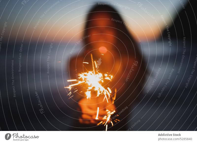 Woman with sparkler on seashore woman burn smile happy celebrate stand cheerful bengal female coast light festive casual ocean joy dusk twilight holiday young