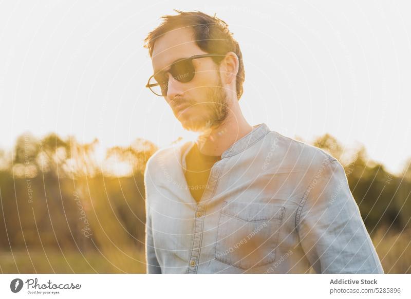 Thoughtful man standing in field countryside sunset meadow pensive nature thoughtful lawn casual male evening sundown hand in pocket grassy eyeglasses serious