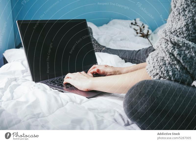 Anonymous female freelancer using computer on bed woman laptop self employed browsing independent typing chat project gadget online connection bedroom lady