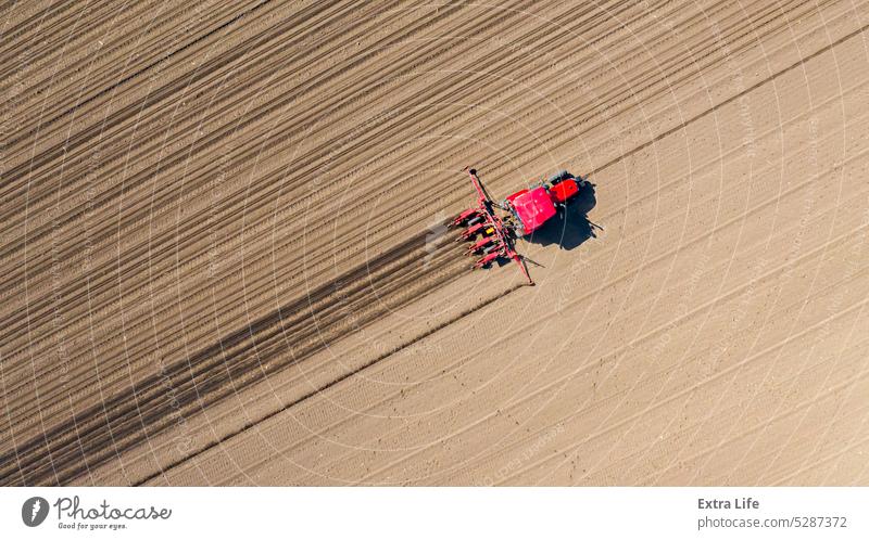 Aerial top view of tractor as dragging a sowing machine over agricultural field, farmland Above Agricultural Agriculture Arable Cereal Corn Cornfield Country