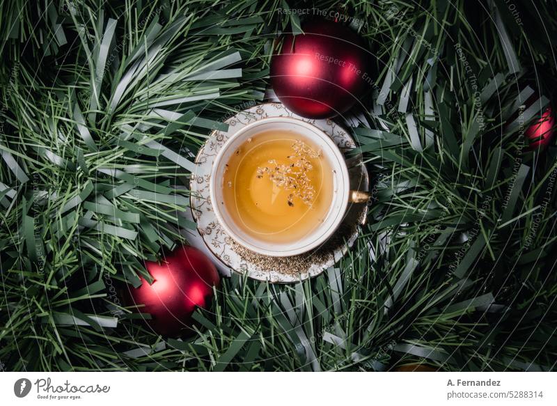 Tea cup filled with herbal tea surrounded by a tinsel and two red Christmas balls tea cup Christmas tinsel Decoration Christmas decor Christmas decoration drink