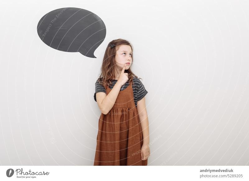 Thoughtful little girl brown-haired child touch chin with finger thinking or considering, pensive lovely daughter making decision imagining idea posing isolated on white studio background. mock up