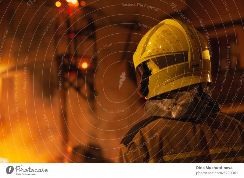 Firefighter closeup from behind standing in from of the fire working. Firemen fighting the flame. arson brushfire burn bushfire challenging crew danger