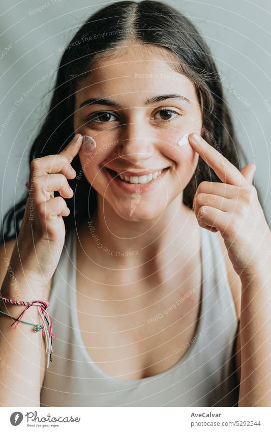 Joyful and funny portrait of a young adult woman with lotion cream on her cheeks. Skincare, face beauty and woman with cream for acne, dermatology and glow on a studio background.