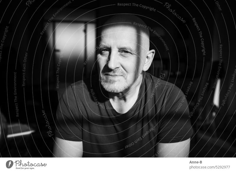 Portrait of a man Between window and door in space Man black-and-white portrait Upper body portrait Light and shadow Looking window light Grating Face shadow