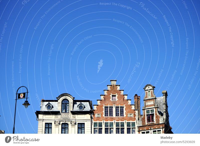 Beautiful restored old houses with decorative gable and stepped gable against blue sky in the sunshine at Korenlei and Gralsburg on the river Leie in Ghent in East Flanders in Belgium