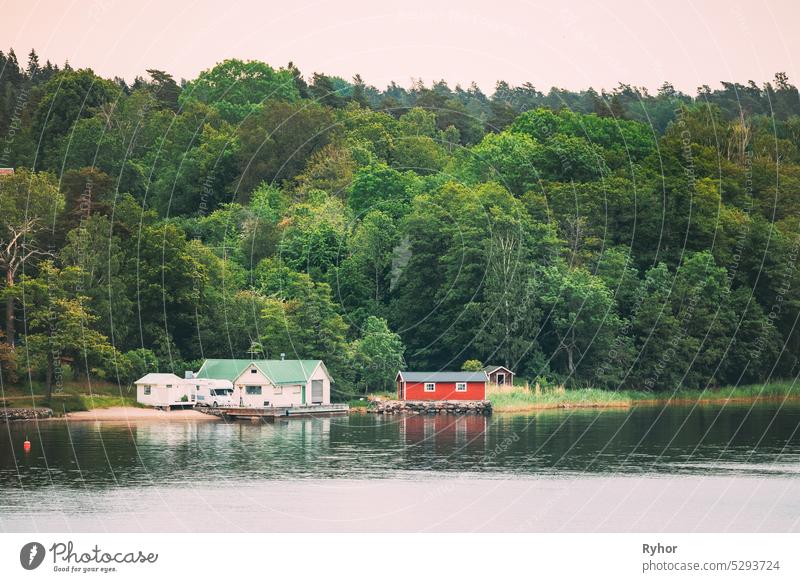 Sweden. Beautiful Red Swedish Wooden Log Cabin House On Rocky Island Coast In Summer. Lake Or River And Forest Landscape apartment archipelago bathhouse