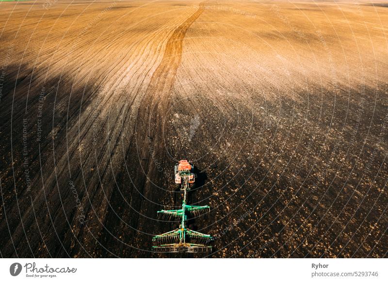 Aerial View. Tractor Plowing Field In Spring Season. Beginning Of Agricultural Spring Season. Cultivator Pulled By A Tractor In Countryside Rural Field Landscape