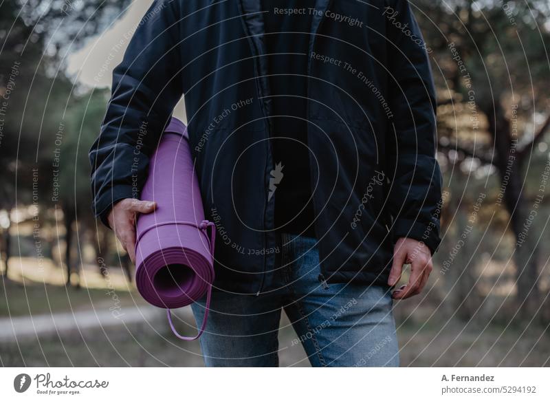 Man holding a purple yoga mat at a park. Concept of doing exerise outside. Man doing yoga. Yoga mat exercise exercise mat violet man boy practise sport