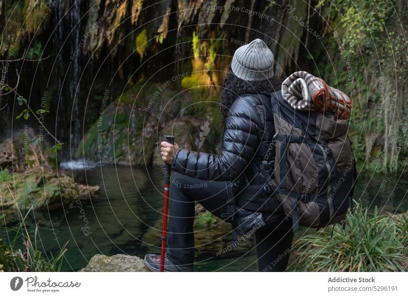 Traveling woman with trekking poles in forest hiker admire lake waterfall nature mountain highland adventure female traveler trip backpack landscape journey