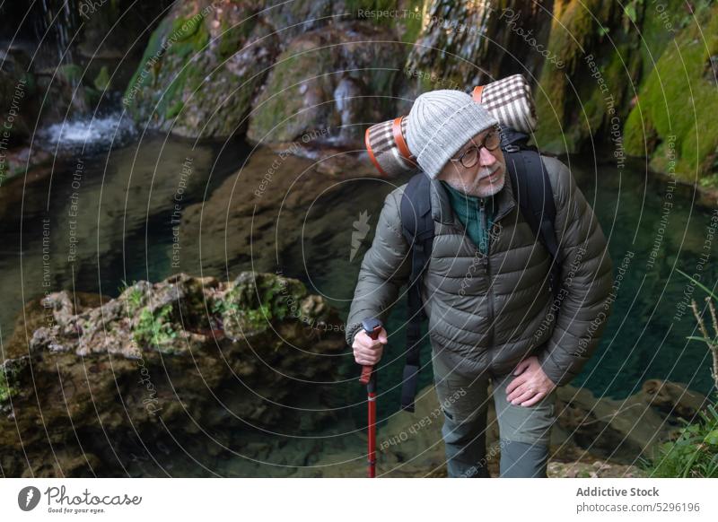 Traveler admiring picturesque view man forest hiker trekking trekking poles traveler waterfall river admire nature explore shore male senior backpack adventure