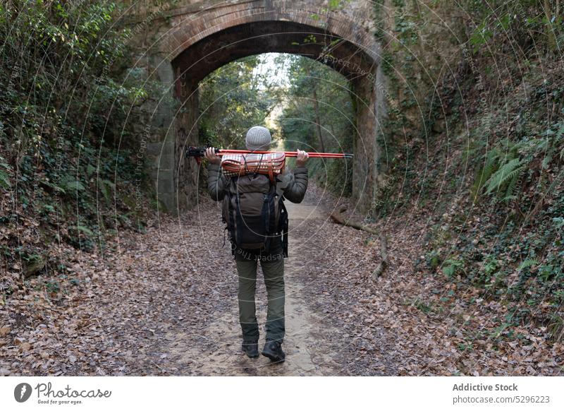 Unrecognizable hiker walking in forest man trekking traveler explore woods nature wanderlust pathway male trip tree backpack pole adventure woodland rucksack