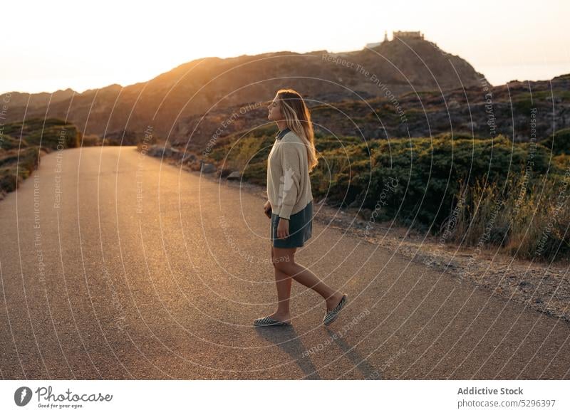 Smiling woman standing with eyes closed against mountains at sundown road sunset summer traveler picturesque leisure trip happy smile female freedom enjoy