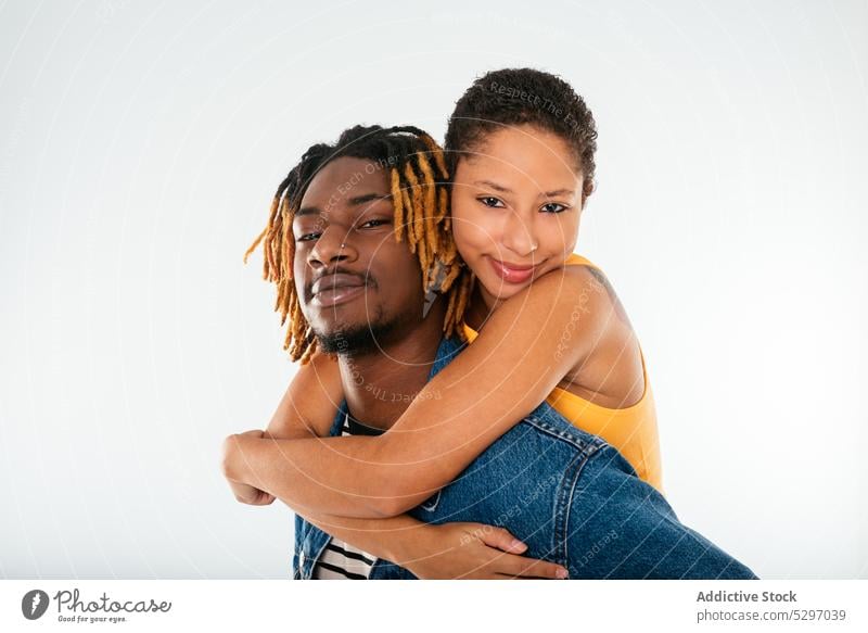 Happy stylish ethnic couple on white background boyfriend girlfriend happy relationship style piggyback ride together studio shot having fun love smile cheerful