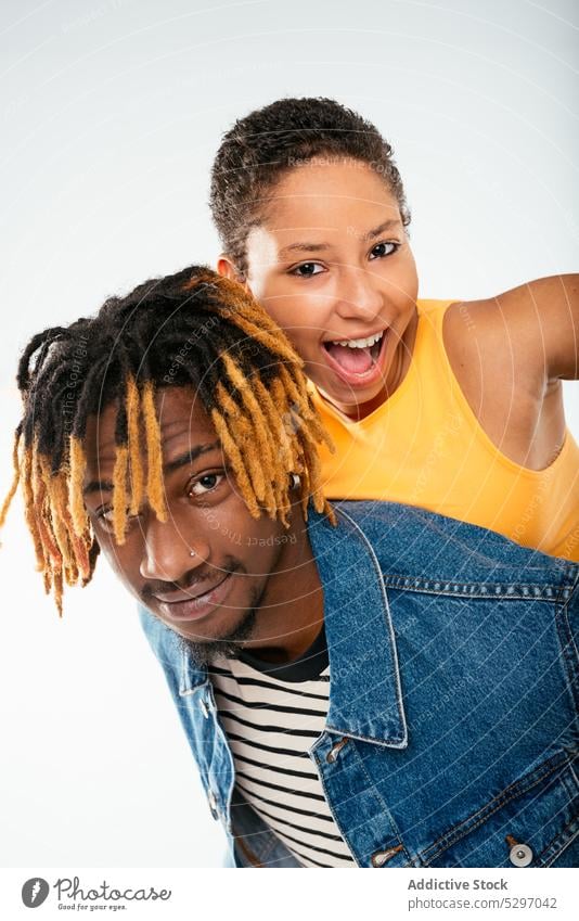 Happy stylish ethnic couple on white background boyfriend girlfriend happy relationship style piggyback ride together studio shot having fun love smile cheerful