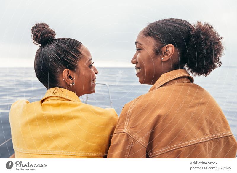 Cheerful black women looking at each other against sea yacht smile beach summer rest friend relax happy together ethnic girlfriend african american weekend