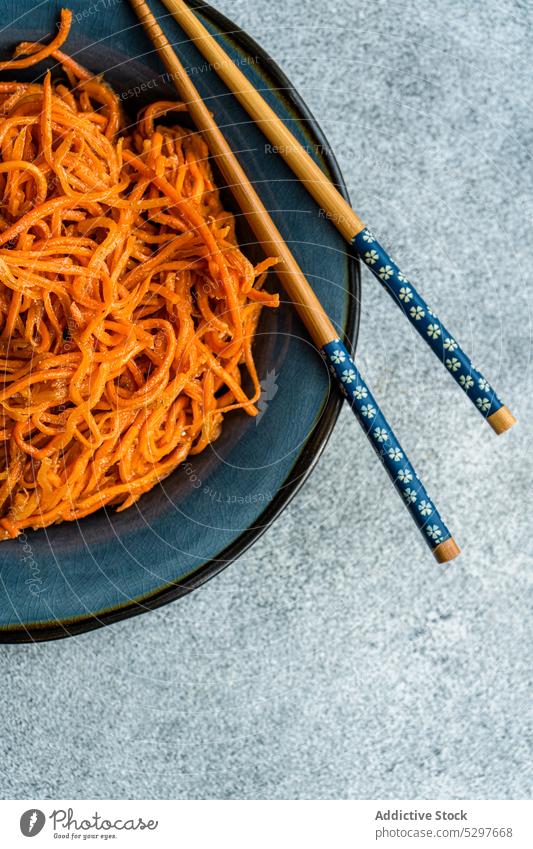 Spicy asian carrot salad chopsticks ceramic plate concrete cuisine grated eat eating food gourmet herb hot chilli korean carrots orange meal napkin pepper