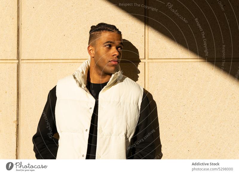 Stylish black man in trendy outfit standing on street city style confident urban wall modern young male african american ethnic serious personality appearance