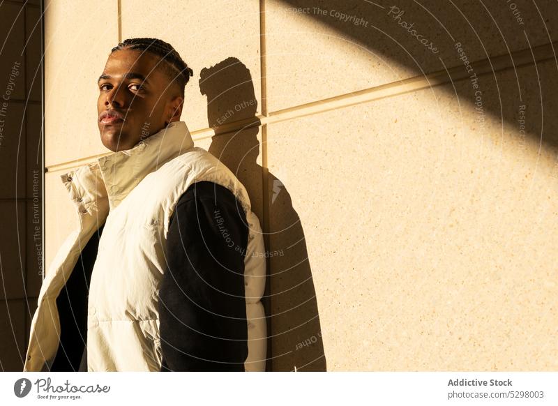 Stylish black man in trendy outfit standing on street city style confident urban wall modern young male african american ethnic serious personality appearance