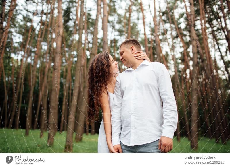 A couple in love beautiful young man and woman are hugging in a summer park on a sunny day. Date outside, well dressed, so excited and lovely happy together