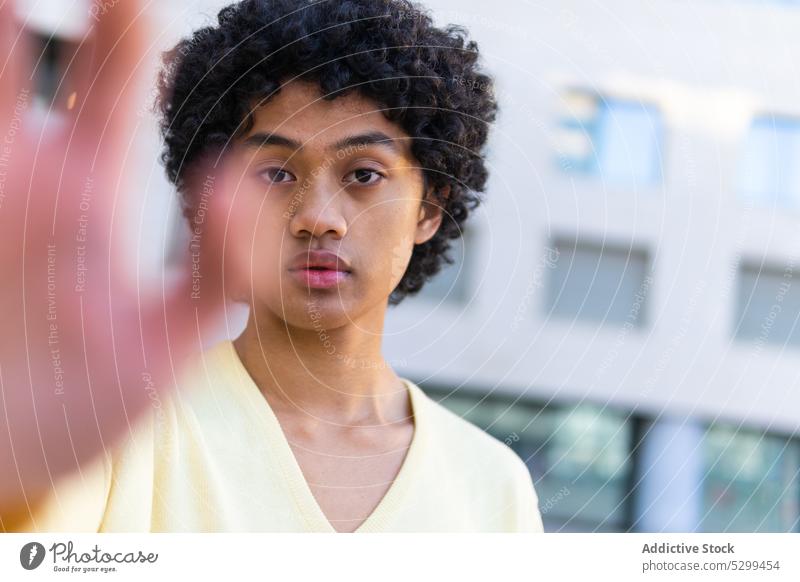 Serious ethnic man showing hand to camera confident street casual urban style modern shirt cool outstretch young serious male curly hair handsome millennial