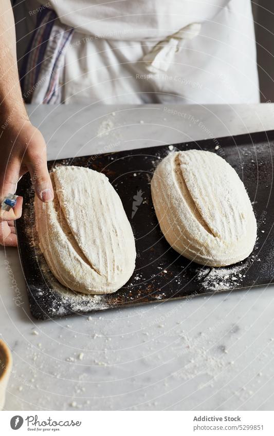 Crop baker scoring sourdough bread cut craft cook pastry table prepare kitchen bakery process raw fresh food uncooked culinary ingredient apron flour