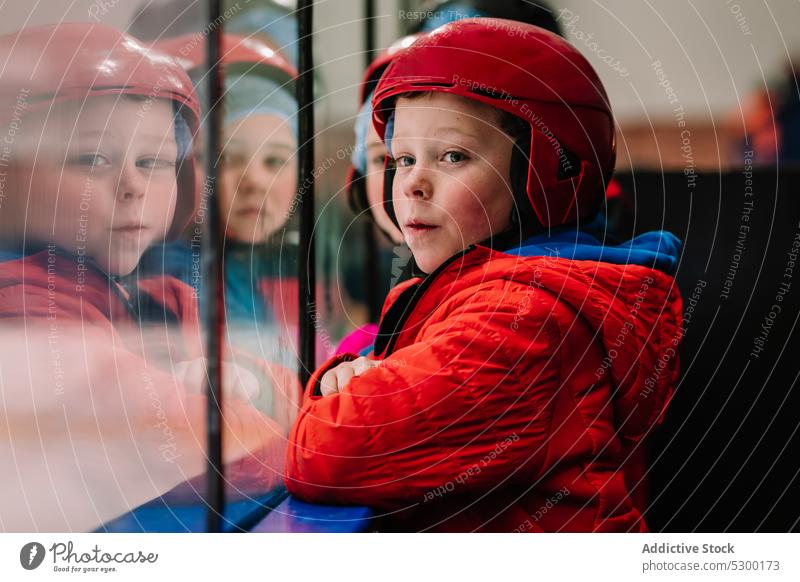 Pensive boy looking at ice rink winter kid safety thoughtful fence protect cold pensive serious helmet season child activity sport outerwear childhood frozen