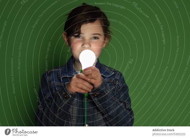 Little girl with light bulb in dark room child kid curious lamp glow female illuminate studio shot cute adorable preteen childhood close stand little green