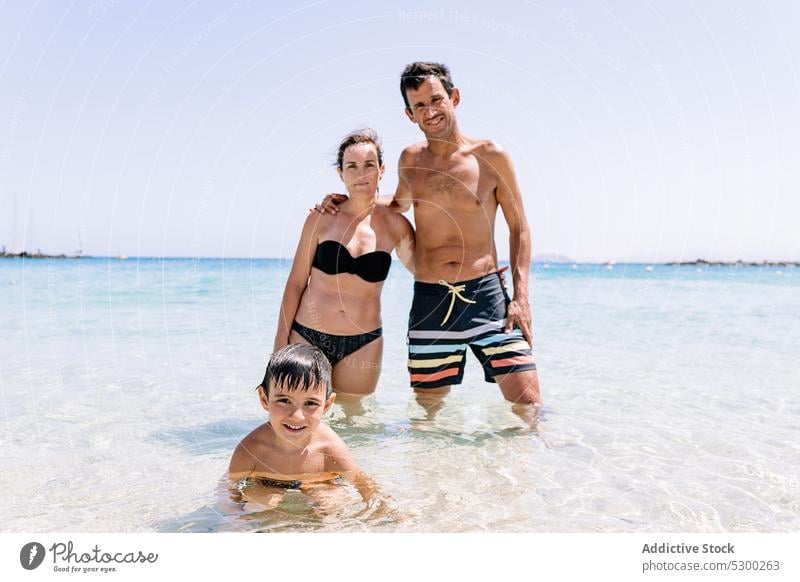 Happy family having fun on beach sea smile resort vacation happy summer holiday swimwear outdoors together enjoy ocean weekend pleasure optimist positive