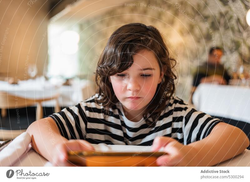 Focused girl watching video on smartphone in restaurant using concentrate online cafe gadget browsing device focus kid internet surfing mobile child interesting