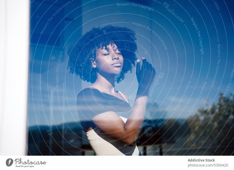 Trendy black woman with eyes closed near window calm serious afro pensive reflection hairstyle home female african american woman young thoughtful curly hair