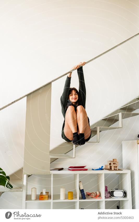 Content woman hanging on rail in apartment smile happy staircase style home positive wall casual female cheerful stairway young step joy optimist modern