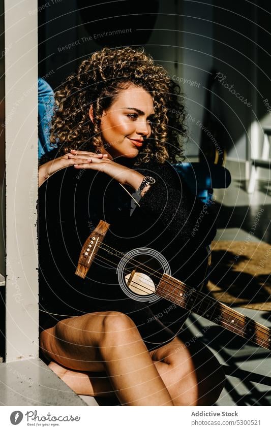 Focused woman playing guitar on floor music musician instrument guitarist practice window hobby acoustic female young melody talent sound home concentrate song