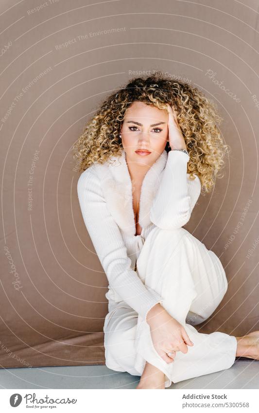 Confident woman in white clothes sitting on floor model studio shot makeup gorgeous charismatic confident self assured appearance individuality young