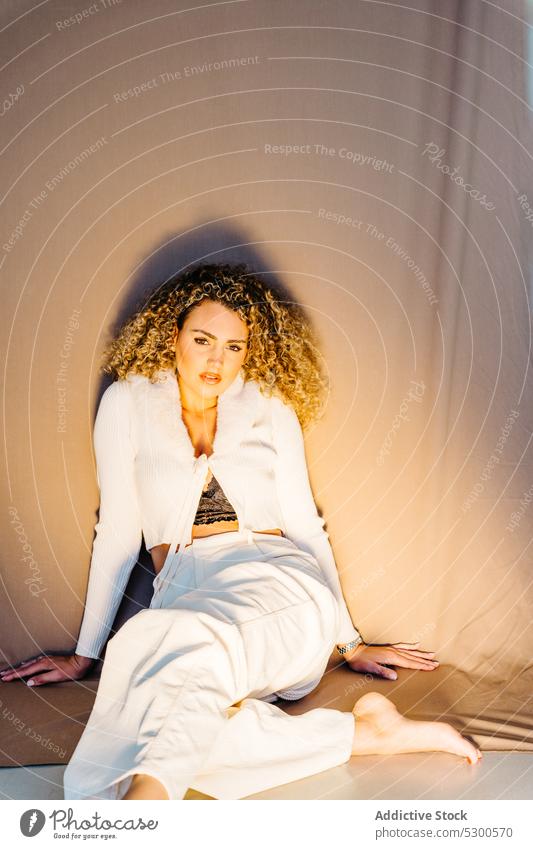 Confident woman in white clothes sitting on floor model studio shot makeup gorgeous charismatic confident self assured appearance individuality young