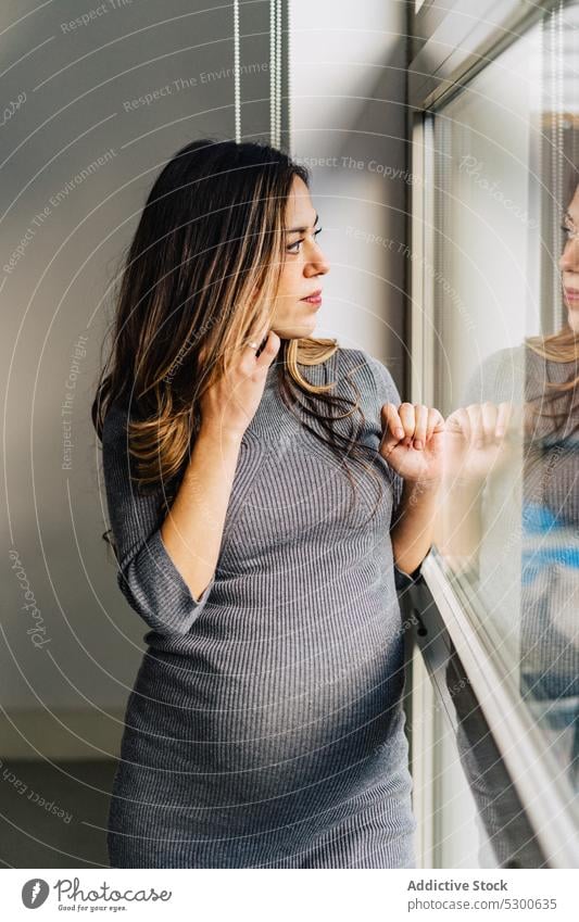 Smiling pregnant woman talking on cellphone using smartphone speak window phone call apartment conversation communicate positive smile female young