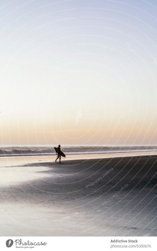 Silhouette of unrecognizable person with surfboard walking along seashore beach sunset sand evening wave surfer coast sundown water mauritania summer ocean