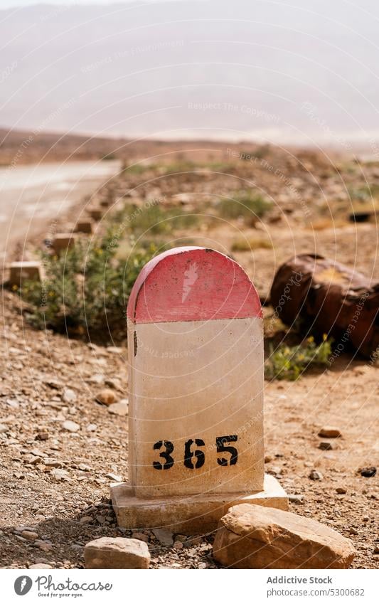 Stone road marker in desert stone rocky road sign old rough nature aged number ground mauritania sahara cloudless route sky cliff blue sky shabby street trip