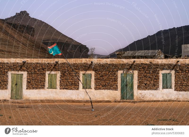 Stone building with flag on pole mountain architecture stone old facade shabby heritage exterior window mauritania sahara aged construction national terrain