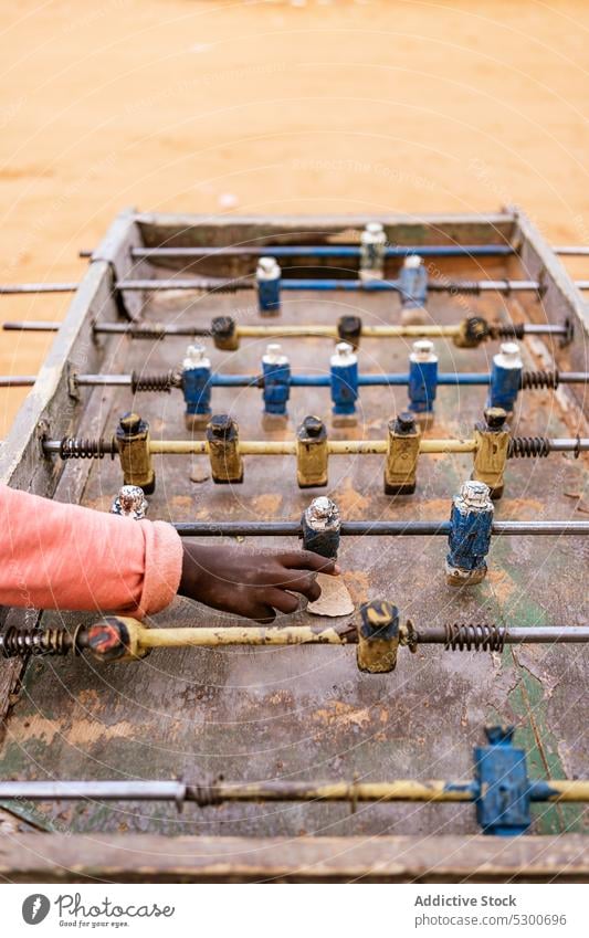 Crop African kid playing mini football on foosball table children childhood soccer game poverty rust figurine miniature old sahara mauritania africa metal