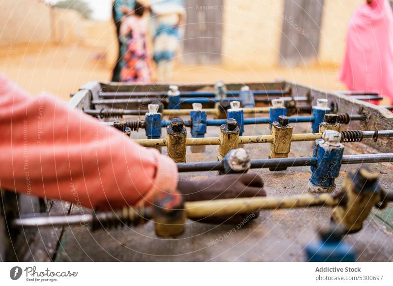 Crop African kids playing mini football on foosball table children childhood soccer game poverty rust figurine miniature old sahara mauritania africa metal