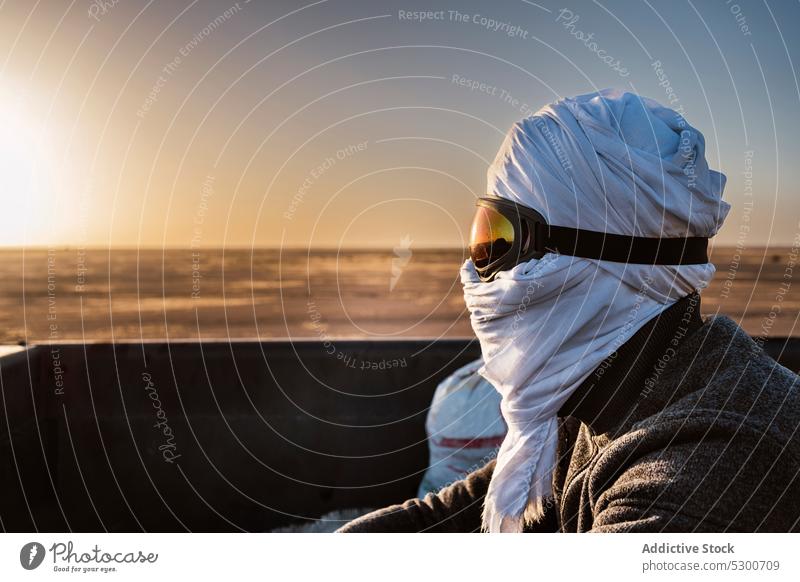 Mauritanian man in traditional headscarf in desert goggles sunset protect traveler male safety adventure countryside sahara mauritania nature sundown trip