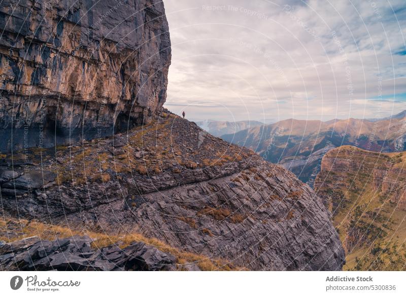 Person standing on rocky mountain slope under cloudy sky person traveler danger nature rough uneven formation ordesa pyrenees of huesca spain europe daylight