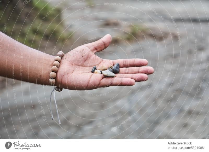 Person showing small stones in canyon person traveler palm hand rock desert tatacoa colombia tourism explore discover demonstrate handful hike destination