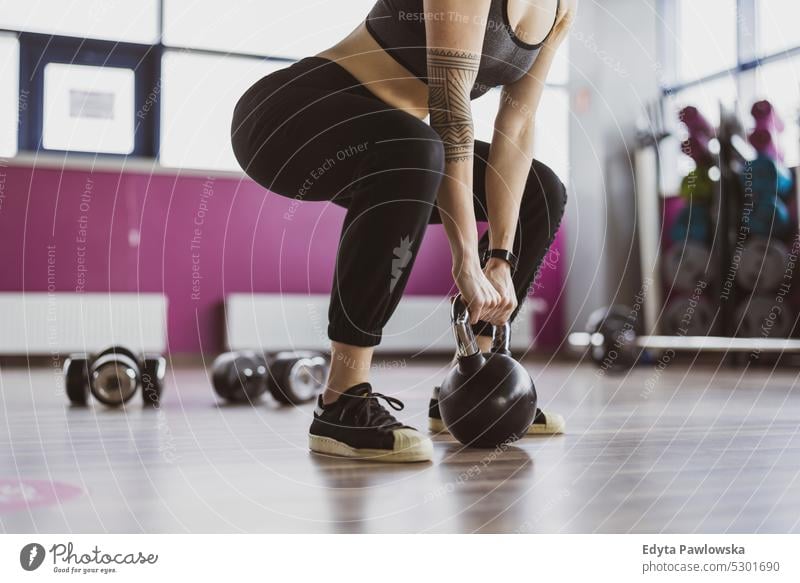 Young woman lifting Kettle bell while crouching in gym wellness wellbeing bodybuilder sporty biceps muscles barbell bodybuilding people muscular adult person