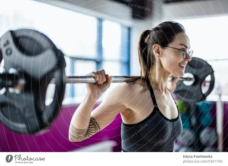 Young woman working out with a barbell at the gym wellness wellbeing bodybuilder sporty lifting biceps muscles bodybuilding people muscular adult person