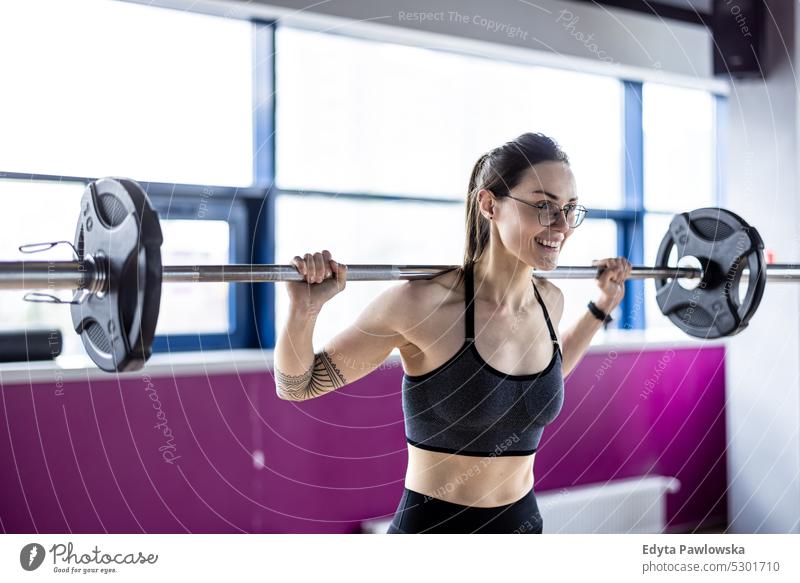 Young woman working out with a barbell at the gym wellness wellbeing bodybuilder sporty lifting biceps muscles bodybuilding people muscular adult person