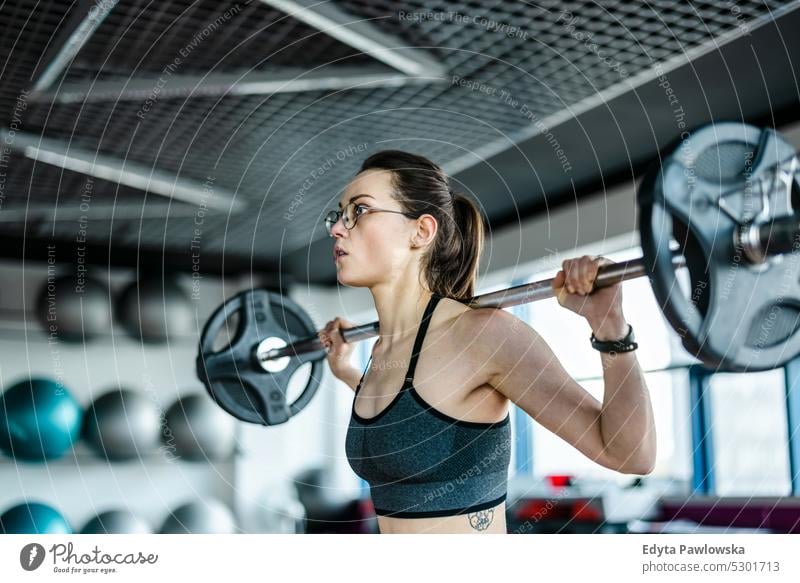 Young woman working out with a barbell at the gym wellness wellbeing bodybuilder sporty lifting biceps muscles bodybuilding people muscular adult person