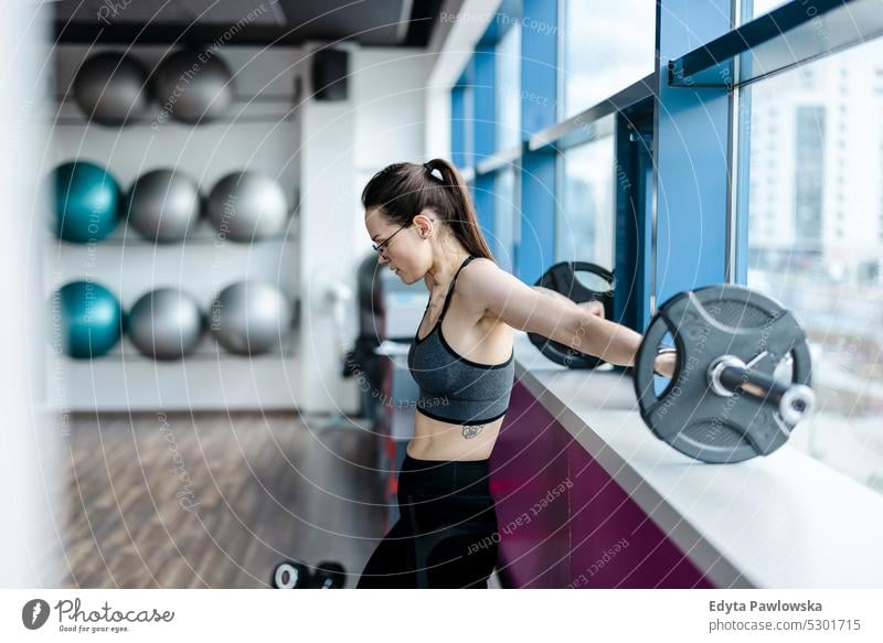 Young woman working out with a barbell at the gym wellness wellbeing bodybuilder sporty lifting biceps muscles bodybuilding people muscular adult person